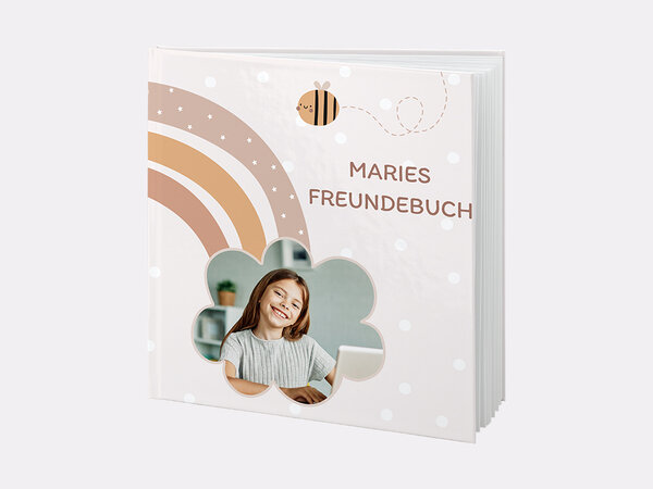 Das Bild zeigt ein personalisiertes Freundebuch im Regenbogen-Design mit Fotoausschnitt in Blütenform und dem Namen Marie.